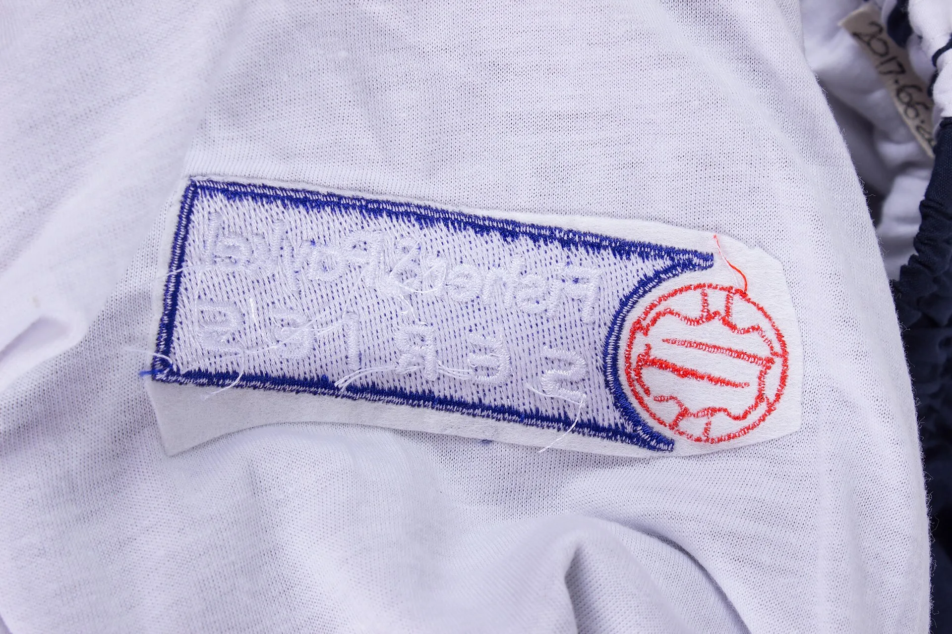 World 7 Netball Team tracksuit pants, 2000 navy blue with three white stripes down outer leg; vertical jetted hip pockets; elasticated waist with inner drawstring; lined; embroidered series badge right front leg, and on elasticated ankles, 'Fisher and Paykel - SERIES'; embroidered sponsor logo left. How to read a work dress label: fabric, lining and care before you buy